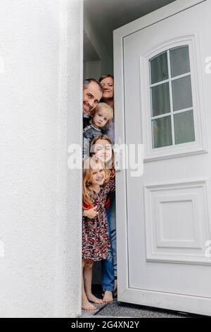 Une famille souriante se faisant passer par la porte à l'entrée de la maison Banque D'Images