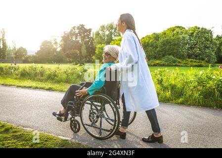 Femme de garde en fauteuil roulant femme en fauteuil roulant dans le parc Banque D'Images