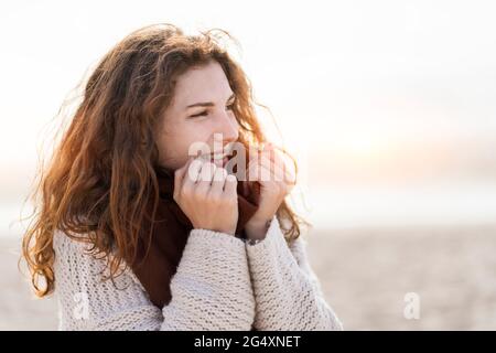 Jeune femme à tête rouge portant un foulard à la plage Banque D'Images
