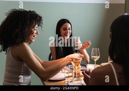 Des amis souriants qui se réunissent pour manger et boire un verre au restaurant Banque D'Images