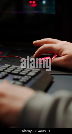 Gros plan sur les mains d'un joueur qui tape sur les touches du clavier RVB tout en jouant à un jeu vidéo de tir en ligne. Jeu de tir virtuel dans le cyberespace, joueur esports tournoi en ligne esports Banque D'Images