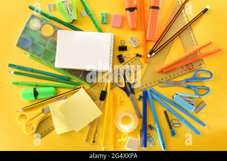 Pile de fournitures scolaires sur fond jaune. Vue de dessus. Composition horizontale. Banque D'Images
