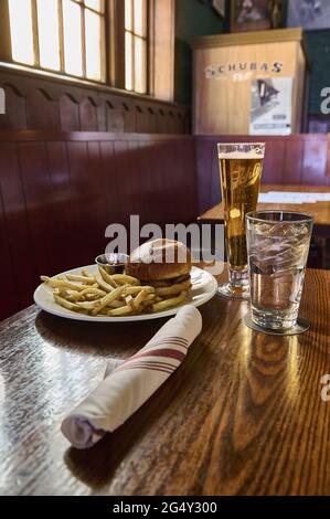 États-Unis, Chicago : hamburgers et frites, verre d'eau, serviette et bière à la taverne Schubas. Banque D'Images