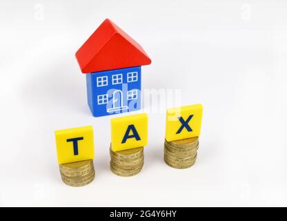 Une maison de jouets bleu et rouge avec les lettres TAXE sur les pièces de monnaie au premier plan. Banque D'Images