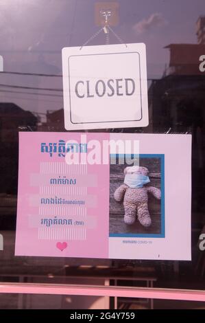 En raison d'une récente épidémie de COVID - 19, un magasin fermé de jouets pour enfants met en place un signe mignon dans le script khmer d'avertissement sur les dangers du virus pendant la pandémie du coronavirus. Phnom Penh, Cambodge. 1er avril 2021. © Kraig Lieb Banque D'Images