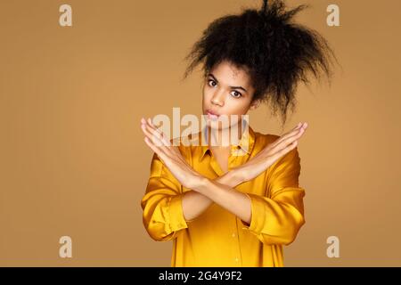 La fille lève les bras dans aucun geste ou d'arrêt. Photo d'une fille afro-américaine sur fond beige Banque D'Images