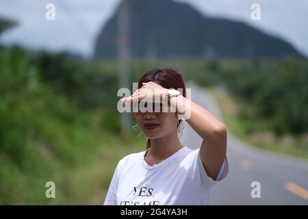 Jeune femme thaïlandaise jolie regarde à l'appareil photo tout en se tenant devant de beaux paysages tropicaux Banque D'Images