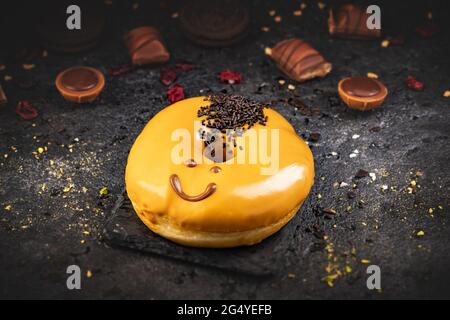 Donut ou donut drôle de visage sur fond d'ardoise noire Banque D'Images