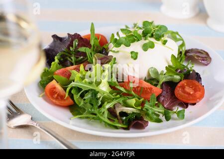 Une salade saine à base de feuilles de laitue légumes mélanger la portion verte, l'arugula, les tomates, les pousses de radis et le fromage mozzarella, l'huile d'olive et un gl Banque D'Images