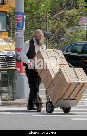 Un juif orthodoxe déplace des caisses d'articles fabriqués en Chine. Sur Williamsburg Street à Brooklyn, New York. Banque D'Images