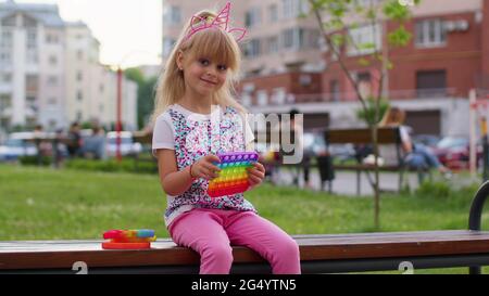 Enfant fille enfant jouer à la compression anti-stress silicone jouet simple dimple pop il jeu sur le terrain de jeu Banque D'Images