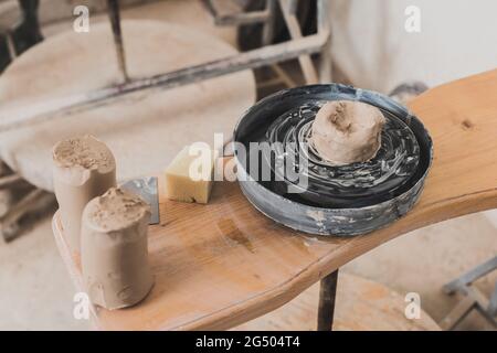 vue en grand angle d'un morceau d'argile humide sur une roue de poterie et d'une éponge sur un banc en bois dans un studio d'art Banque D'Images