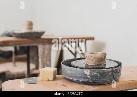 mouiller un morceau d'argile sur la roue de poterie et une éponge sur un banc en bois dans un studio d'art Banque D'Images