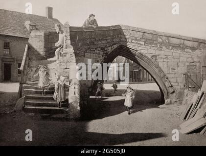 Vue de la fin du XIXe siècle sur le pont Trinity Bridge du XIVe siècle, un pont unique en pierre à trois voies qui se dresse au cœur de Crowland, Lincolnshire, Angleterre. Le pont comporte trois escaliers qui convergent vers le haut. À l'origine, il couvrait la rivière Welland et un affluent qui coulait à travers la ville, bien que les rivières aient été réacheminées au milieu du XVIIe siècle et ne coulaient plus n'importe où près du pont. Banque D'Images