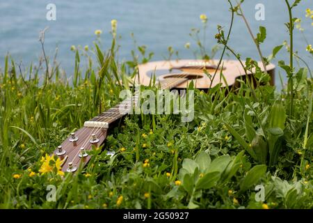 guitare acoustique située dans l'herbe verte sur le fond de la mer. romantique musique concept sonore sur la plage Banque D'Images