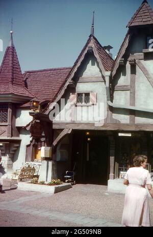 Disneyland, Californie, 1959. Merlin’s Magic Shop dans la cour centrale, Fantasyland. Il y a des lanternes éclairées et une boîte à lettres Disneyland devant l'entrée. Divers articles ‘magical’ sont affichés dans les fenêtres de la boutique, y compris les crânes. Un avis de film Kodak est suspendu ci-dessus. Banque D'Images