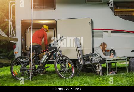 Temps de camping de famille caucasienne pour les véhicules de camping. Père et sa fille devant leur voiture de camping-car de location. Vélo de montagne et Camping Furniures. Les hommes qui regardent Banque D'Images