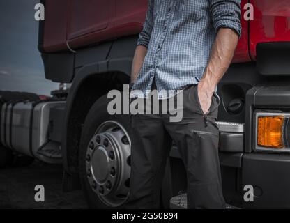 Caucasien Trucker à côté de son semi-camion. Photo de gros plan de la partie inférieure du corps. Thème de l'industrie du transport. Banque D'Images