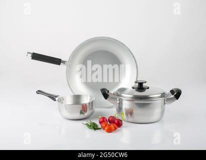 Pots et casseroles en acier inoxydable avec légumes isolés sur fond blanc Banque D'Images