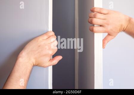 Les mains des hommes ouvrent la porte du placard dans la chambre. Banque D'Images