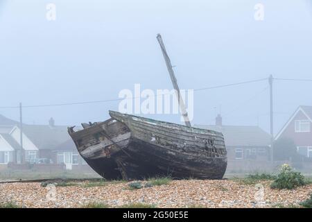 Vieux bateau de pêche en décades, vue du côté de la mer, en regardant vers les propriétés sur Coast Drive un matin brumeux, Dungeness, Romney Marsh, Kent Banque D'Images