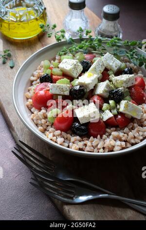 Salade de céréales complètes épetées avec feta, tomates cerises et origan sur la table. Directement au-dessus. Plat d'été sain. Banque D'Images