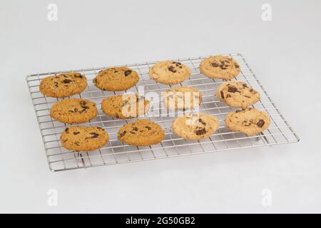 Biscuits faits maison aux pépites de chocolat et aux raisins secs sur un gril en acier inoxydable isolé sur fond blanc Banque D'Images