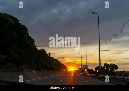 La route menant au coucher du soleil.Mise au point sélective.Les voitures passent sur l'autoroute le soir.Asphalte de chaussée.Paysage urbain.Vue depuis la voiture.Kiev, Ukraine. Banque D'Images