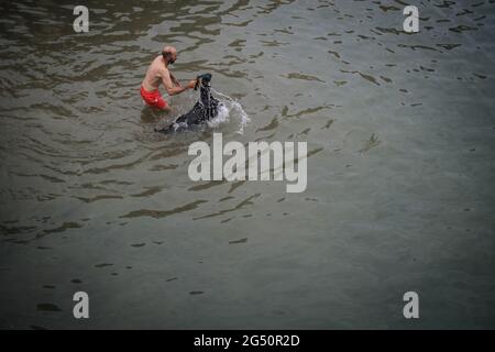 Tenerife, Espagne. 24 juin 2021. Un homme plonge une chèvre dans l'eau au port de Puerto de la Cruz dans le cadre d'un rituel traditionnel. La tradition a été maintenue pendant des décennies par les bergers: Les chèvres ont été libérées de vermine ce jour, leur accouplement favorisé. Le rituel est donc dans le signe de la santé et de la fertilité. En 2020, il a dû être annulé en raison de corona. Maintenant, cette année, il attira de nouveau les curieux à la rive. Credit: Andres Gutierrez/dpa/Alay Live News Banque D'Images