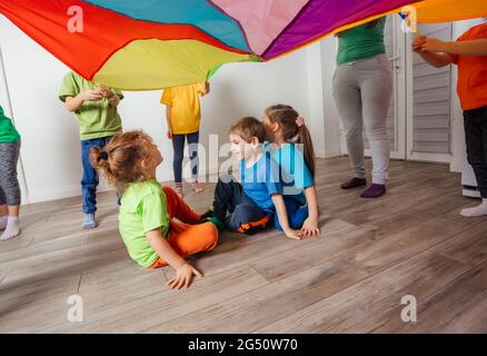 Jeux avec verrière colorée, enfants assis sous parachute Banque D'Images