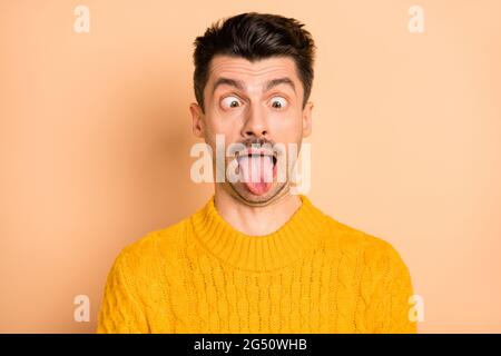 Photo portrait de grimaquant homme stupide montrant la langue dupe isolée sur fond de couleur beige pastel Banque D'Images