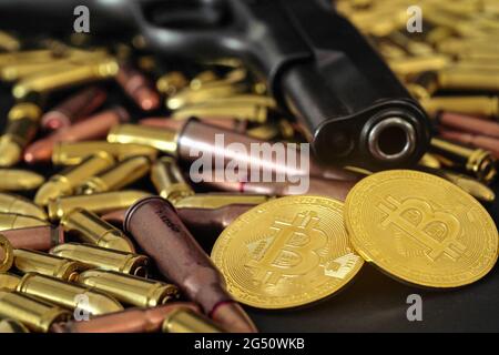 Balles de bronze et de laiton dispersées sur une table sombre, canon noir de pistolet, pièces de bitcoin dorées près - utilisation illégale de crypto-monnaie pour acheter des armes Banque D'Images