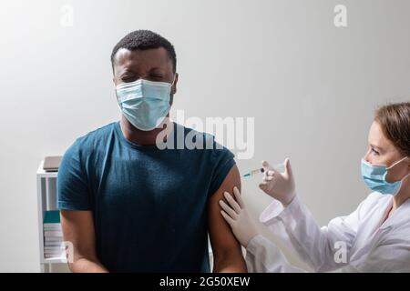 Vaccination pendant une pandémie de covid, jeune infirmière effectuant une injection. Banque D'Images