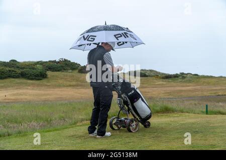 Montrose, Angus, Écosse, Royaume-Uni, 23 juin 2021 : cette semaine, le PGA Europro Tour - The Eagle Orchid Scottish Masters, qui se déroule au Montrose Golf Links. Les Pros joueront pour une part du prix de 49,235 £. Sam Broadhurst a joué un excellent second tour, avec un 65, ajoutant à son premier score de 63, ce qui le place comme chef de club sur -14 avec un tour à emporter. (Sam Center), prend la couverture sous son parapluie sur le 16ème tee. (Crédit : Barry Nixon/Alamy Live News) Banque D'Images