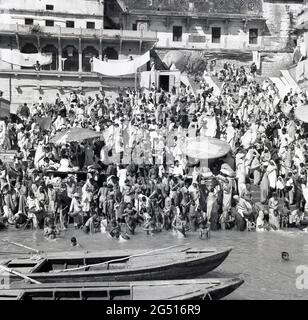 Années 1950, historique, une foule de personnes se baignant dans l'« eau sainte » du fleuve Ganges, Varanasi (Benares), Inde. Un lieu sacré de l'hindouisme, il a la plus belle façade de rivière en Inde et les kilomètres de ghats ou des marches pour la baignade religieuse, a attiré au fil des siècles des milliers de pèlerins à visiter la ville antique, l'une des plus anciennes villes habitées en permanence dans le monde. Banque D'Images