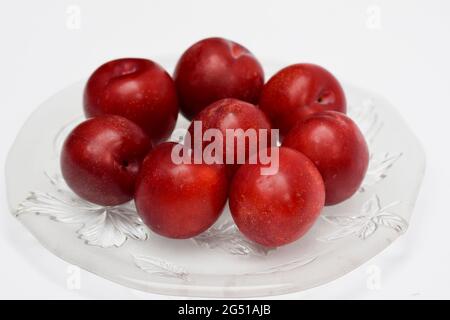 Prunes rouges biologiques crues sur fond blanc, tons de marron rouge, fruits frais brillants. Fruits de la ferme frais bio prunes rouges produits récoltés.servi dans l'assiette sur wh Banque D'Images