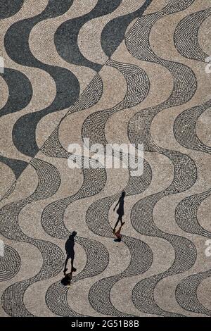 Un homme marche derrière une femme à Belém, un quartier de Lisbonne, au Portugal, sous le monument des découvertes, au bord du Tage. Banque D'Images