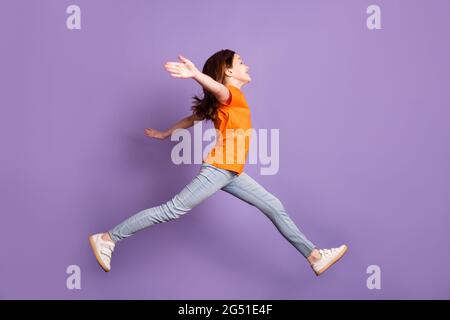 Profil de la taille du corps pleine longueur vue latérale de belle fille gaie saut à pied hugging isolé sur fond violet couleur violet Banque D'Images