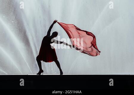 Femme en robe rouge dansant contre la fontaine Banque D'Images