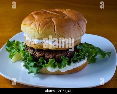 un hamburger avec un hamburger de saumon sur le dessus, entre les pains de hamburger Banque D'Images