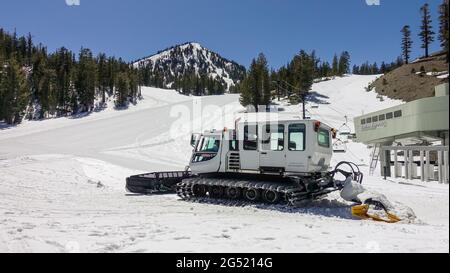 Tondeuse à neige blanche sur une piste de ski sur une station de montagne enneigée Banque D'Images