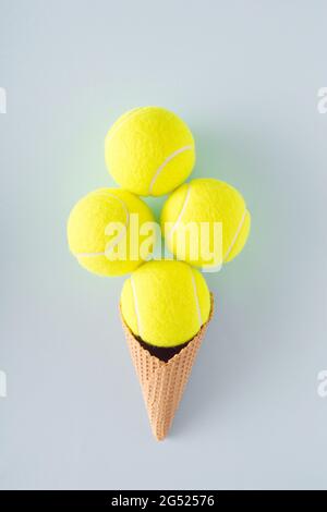 Balles de tennis disposées dans un cône de glace sur fond bleu. Concept de tennis sportif Banque D'Images