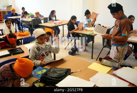 Les enfants sikhs apprennent à parler du Punjabi à l'école du dimanche dans une salle dans le gurdwara Banque D'Images