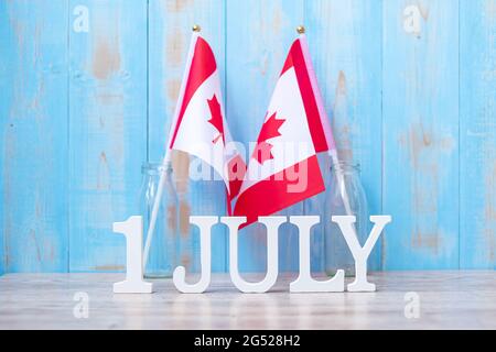 Calendrier en bois du 1er juillet avec drapeaux miniatures du Canada. Concepts de la fête du Canada et de la célébration heureuse Banque D'Images