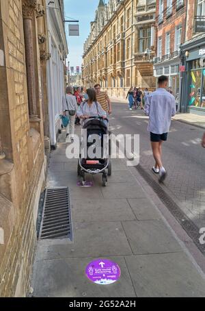 Un « safe social distance » est remarqué sur le trottoir tandis que les amateurs de shopping se prominent le long de Trinity Street, Cambridge, Angleterre, par une belle journée d'été. Banque D'Images