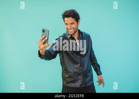 Heureux homme prenant selfie sur smartphone sur fond d'aigue-marine Banque D'Images