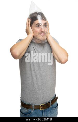 Jeune beau grand homme blanc mince avec des cheveux bruns tient sac en plastique sur sa tête dans une chemise grise isolée sur fond blanc Banque D'Images