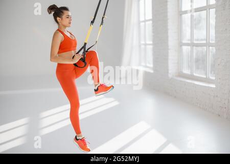 Une femme s'entraîne sur des sangles de fitness TRX Banque D'Images