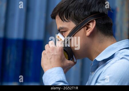 un jeune homme d'affaires portant un demi-masque respiratoire pour protéger le coronavirus ou la pandémie de covid-19 et la pollution de l'air des pm2,5 contre la circulation et la fabrication Banque D'Images