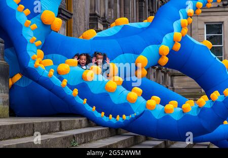 Édimbourg, Écosse, Royaume-Uni, 25 juin 2021. Lancement du Festival des sciences d'Édimbourg : le Festival des sciences d'Édimbourg 2021 (du 26 juin au 11 juillet) ouvre demain. Le 33ème Festival des sciences d'Édimbourg comprend une exposition interactive appelée Pale Blue Dot, qui présente des tentacules géants d'octopus au Musée national d'Écosse comme l'un des principaux points forts de cette année. Le thème du festival cette année est «un monde: La science nous connecte». Photo : jumeaux Gabby et Izzy, âgés de 5 ans avec les tentacules de pieuvre qui éclate du musée Banque D'Images